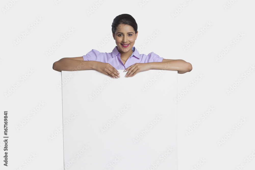 Portrait of smiling businesswoman leaning on empty placard over white background Portrait of smiling businesswoman leaning on empty placard over white background