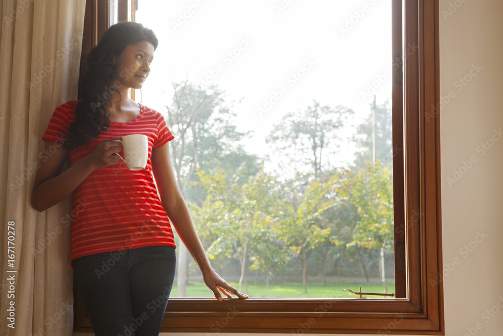 Obraz premium Woman looking out of window