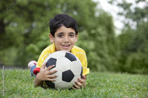 Portrait of young boy lying on grass with ball  © IndiaPix