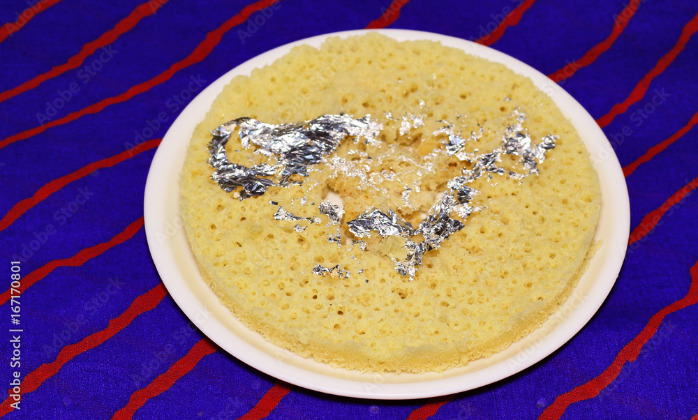 Indian disc-shaped mithai, ghevar sweet garnished with dry fruits and silver leaf. Indian disc-shaped mithai, ghevar sweet garnished with dry fruits and silver leaf.