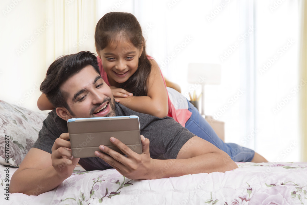 Father and daughter using digital tablet on bed Father and daughter using digital tablet on bed