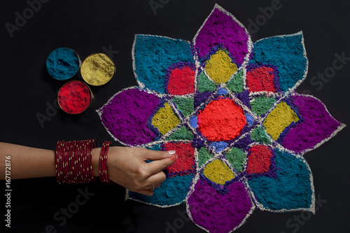 High angle view of woman's hand making rangoli 