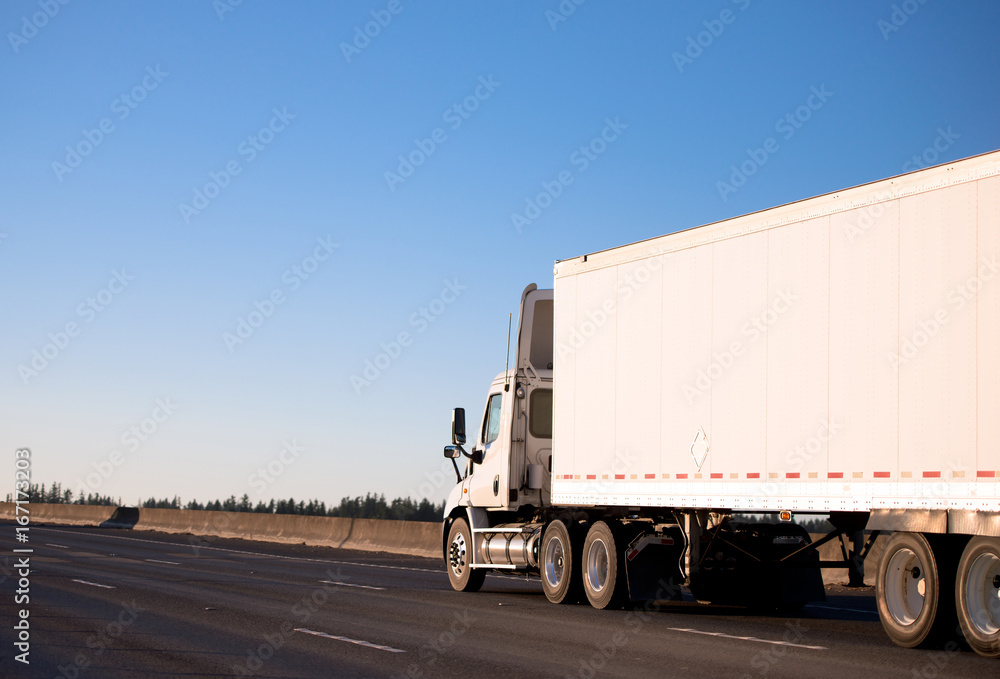 Day cab semi truck with long trailer running on roadway