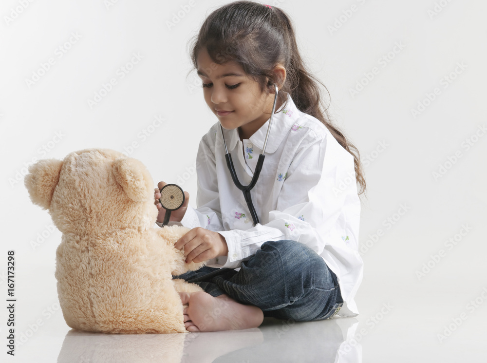 Girl playing doctor with teddy bear Girl playing doctor with teddy bear