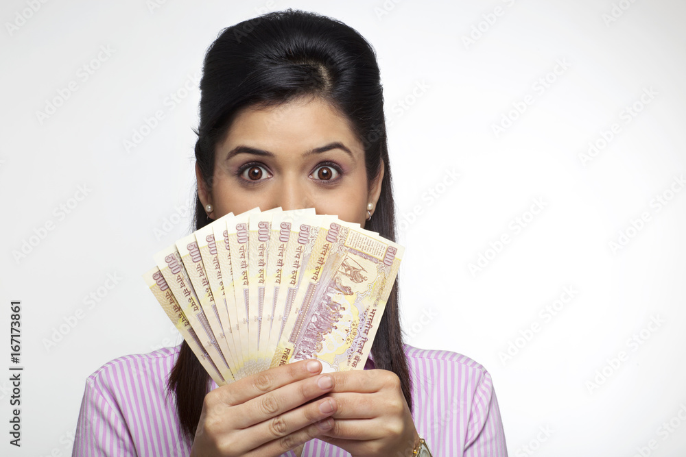 Female executive hiding her face with currency Female executive hiding her face with currency