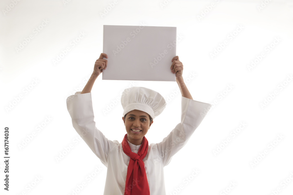 Portrait of female chef holding blank sign board isolated over white background Portrait of female chef holding blank sign board isolated over white background