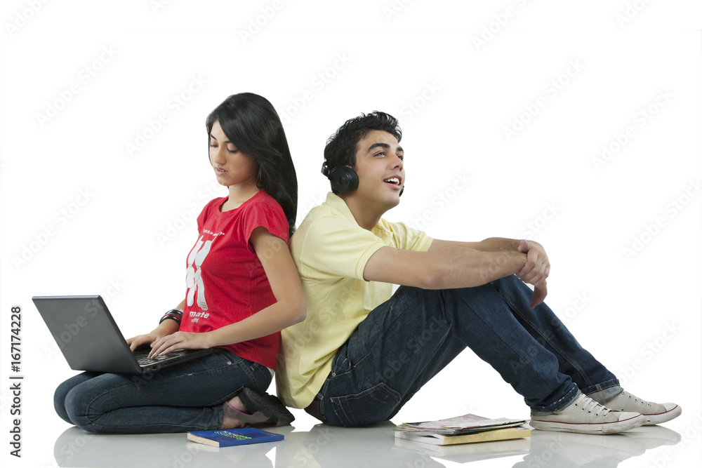 Obraz premium Girl sitting with a laptop while boy listens to music 