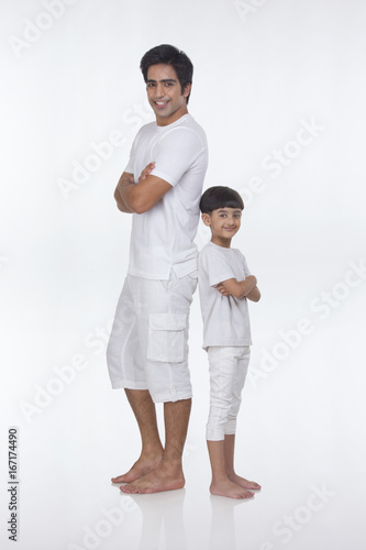 Portrait of father and son standing back to back