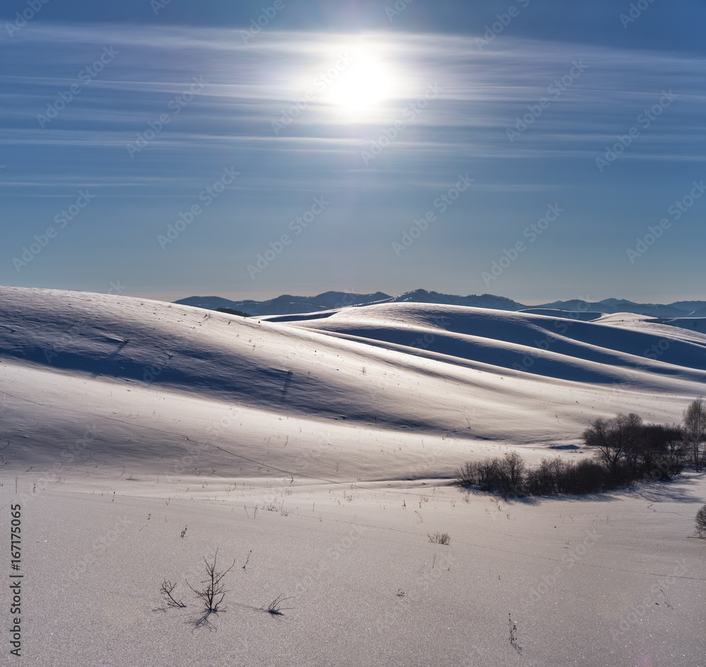 Winter landscape with heels under snow with Sun on blue sky Winter landscape with heels under snow with Sun on blue sky