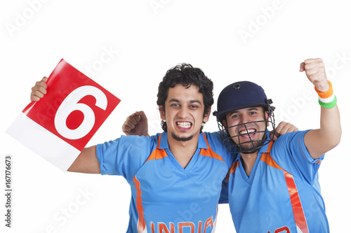 Photography Portrait of cheerful male cricket fans in jerseys standing together over white b