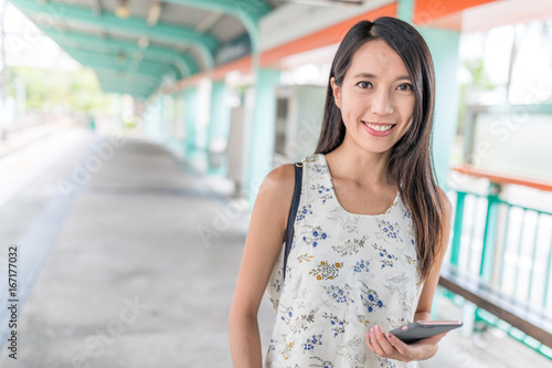 Woman using smart phone in light rail station at Hong Kong photo