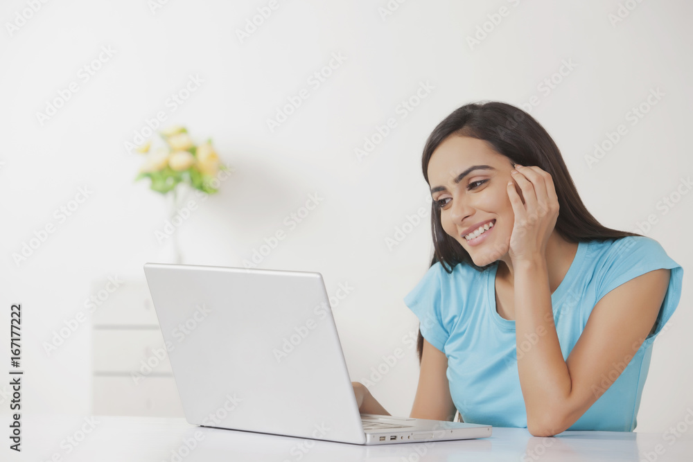 Happy young woman working on laptop at home Happy young woman working on laptop at home