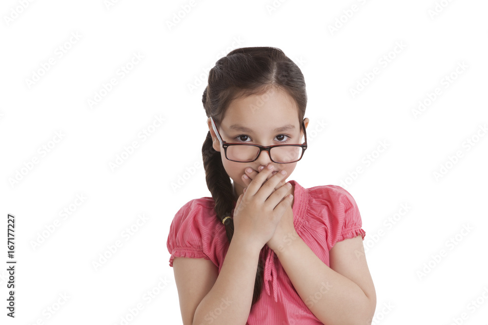 Portrait of little girl covering mouth with hands Portrait of little girl covering mouth with hands