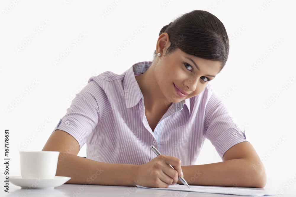 Portrait of smiling female executive writing on paper Portrait of smiling female executive writing on paper