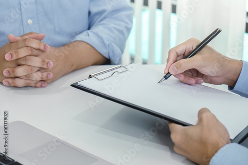 Close up of doctor filling up an history form while consulting patient and recommend treatment methods and how to rehabilitate the body