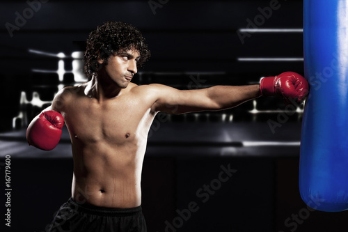 Young man wearing boxing gloves and punching 