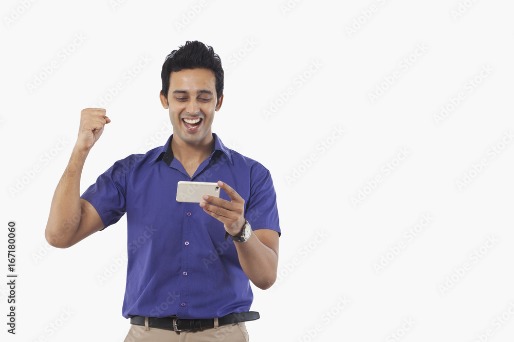Young man cheering while watching a video on mobile phone Young man cheering while watching a video on mobile phone