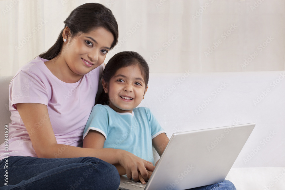 Portrait of woman helping her daughter to use a laptop Portrait of woman helping her daughter to use a laptop