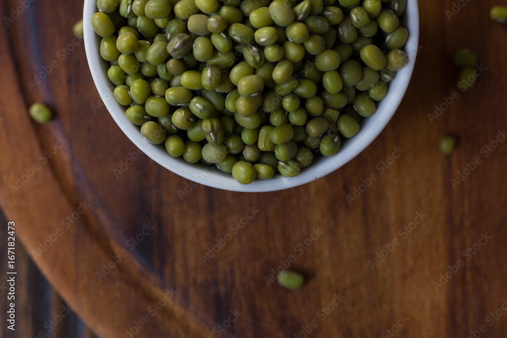 Organic mung beans on white ceramic bowl over wooden background. Organic mung beans on white ceramic bowl over wooden background.