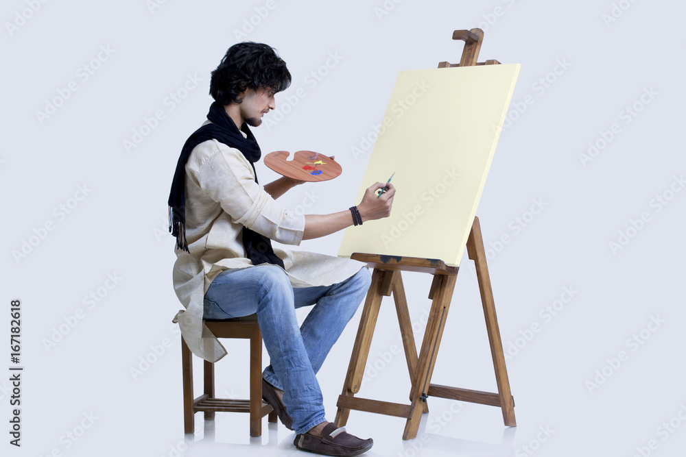 Young male artist about to paint against colored background 
