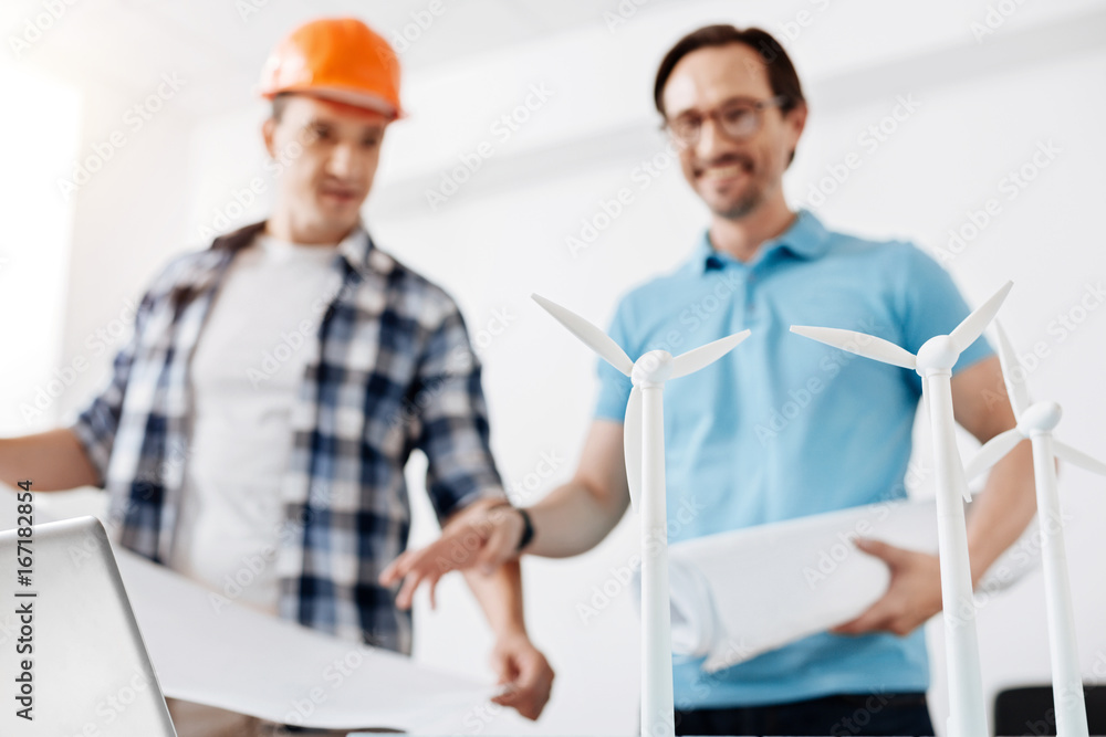 Architect and builder looking at wind power station model Architect and builder looking at wind power station model