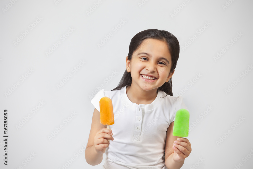 Portrait of happy little girl with ice lollies isolated over gray background Portrait of happy little girl with ice lollies isolated over gray background