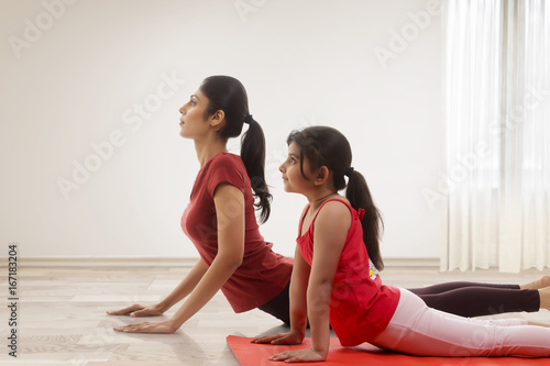 Mother and daughter practicing yoga in home