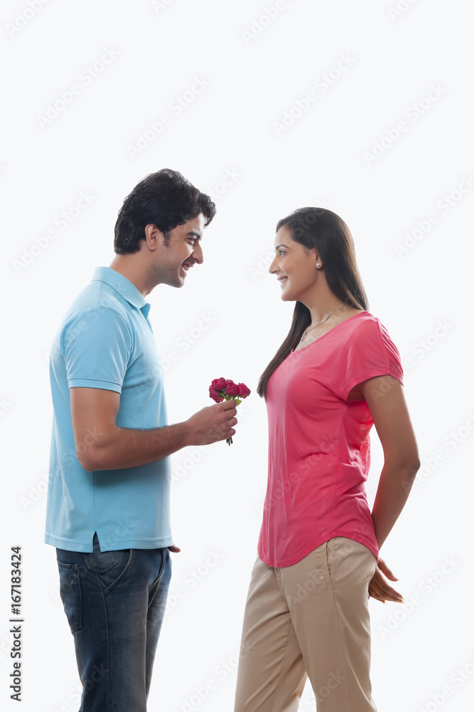 Young man giving rose to woman over white background Young man giving rose to woman over white background