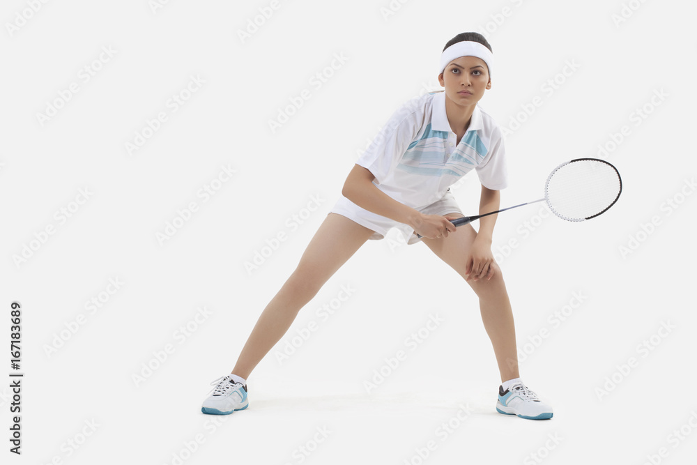 Woman in sports wear playing badminton isolated over white background