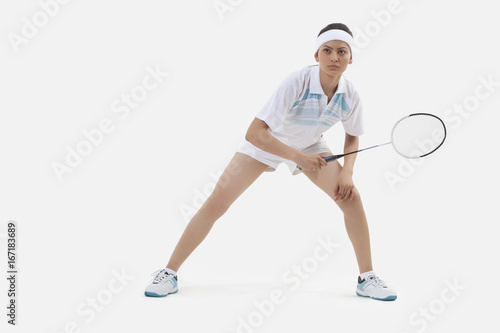 Woman in sports wear playing badminton isolated over white background © IndiaPix