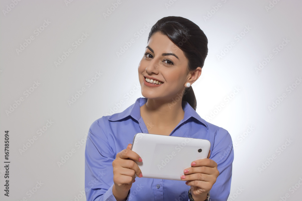 Portrait of confident businesswoman holding digital tablet over gray background Portrait of confident businesswoman holding digital tablet over gray background