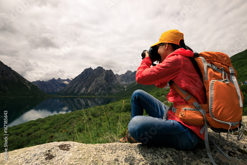 young woman photographer taking photo in mountains