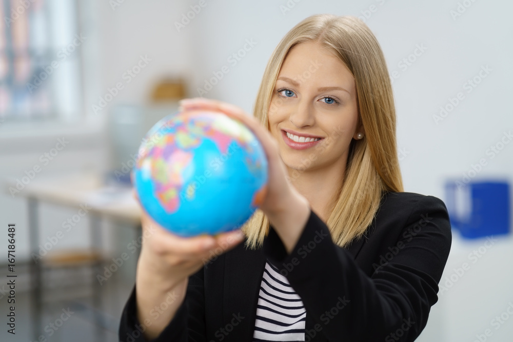 junge frau im büro zeigt eine weltkugel junge frau im büro zeigt eine weltkugel