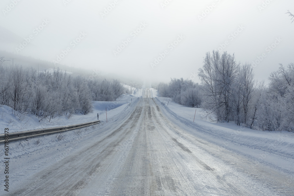 Remote frozen road in fog in winter