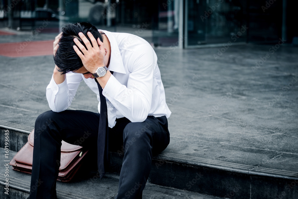 Unemployed Tired or stressed businessman sitting on the walkway after work Stressed businessman concept Unemployed Tired or stressed businessman sitting on the walkway after work Stressed businessman concept