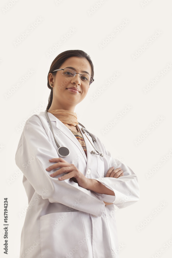Low angle view of young confident female doctor standing against white background Low angle view of young confident female doctor standing against white background
