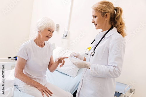 Curious bright elderly woman pointing at pillbox