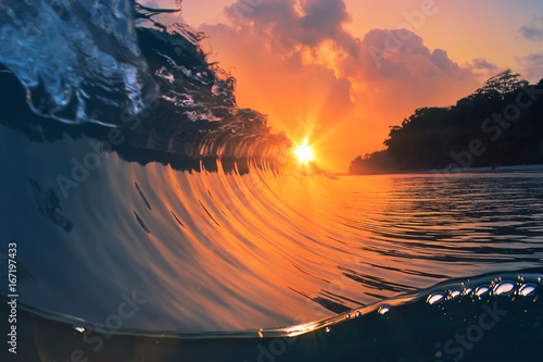 Fototapeta Naklejka Na Ścianę i Meble -  rough colored ocean wave falling down at sunset time