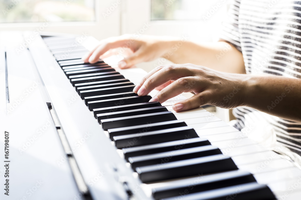 Fototapeta premium A woman playing piano at the window. A cup of coffee is on the instrument