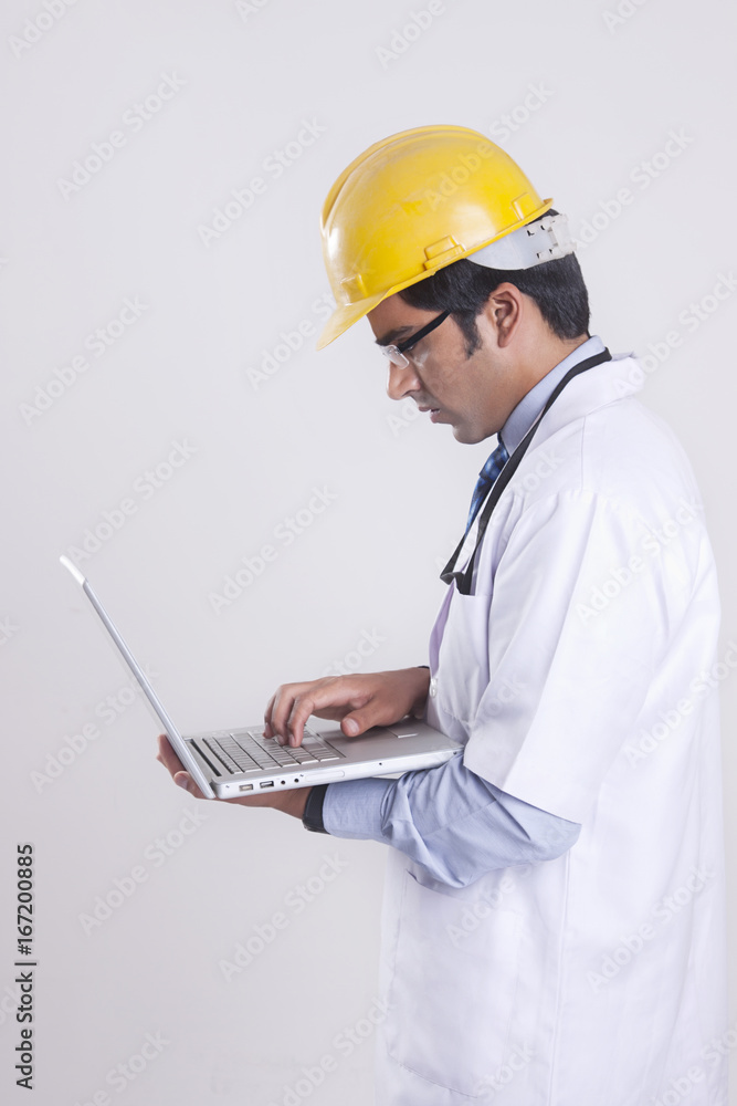 Side view of technician using laptop against gray background Side view of technician using laptop against gray background