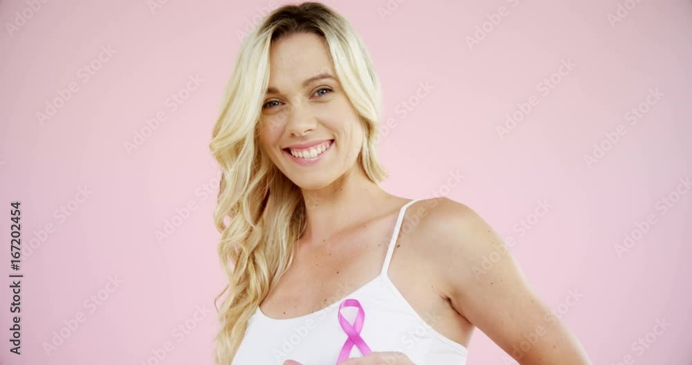 Smiling woman showing breast cancer awareness ribbon Smiling woman showing breast cancer awareness ribbon
