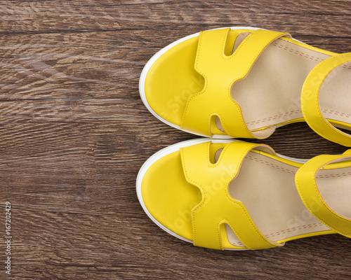 Yellow wedge sandals on dark wooden surface