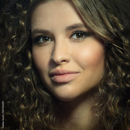 portrait of beautiful young model with curly hairstyle looking into camera