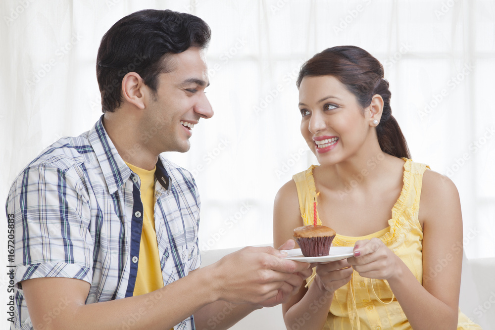 Young couple holding a plate with a cupcake Young couple holding a plate with a cupcake