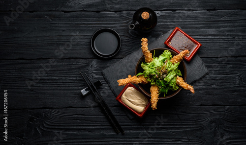 Tempura shrimps with sauces on a dark wooden table