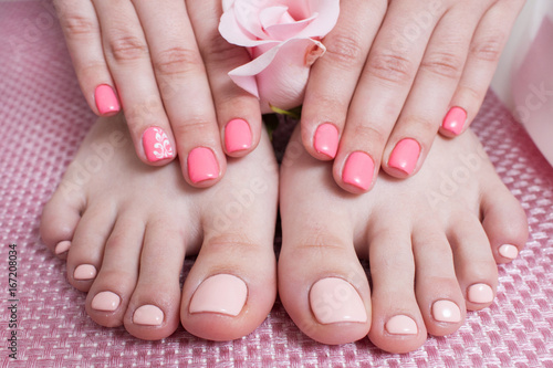 Hands with manicure  feets with pedicure. Female hands and feet on pink background top view. Result of spa salon procedure