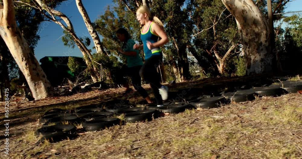 Friends running over tyres during obstacle course Friends running over tyres during obstacle course