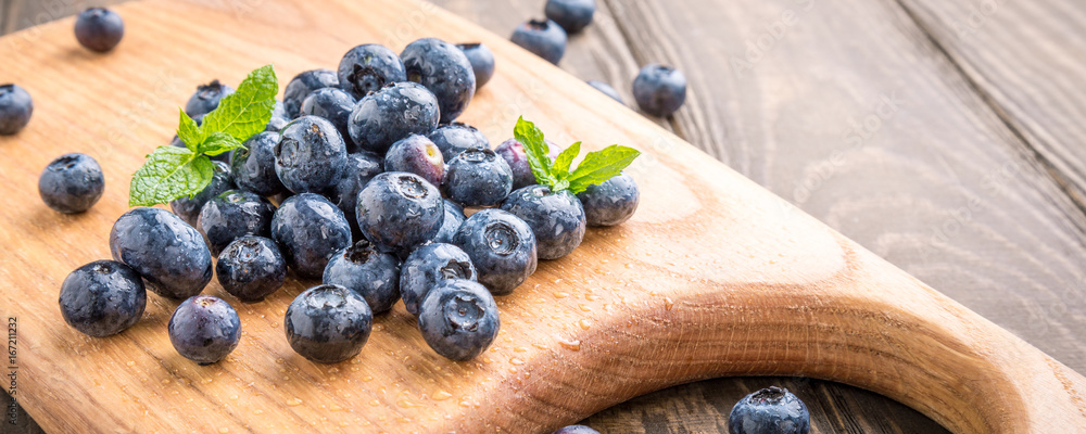 Fresh blueberries on cutting board on old wooden background. Healthy eating and nutrition concept. Banner. Fresh blueberries on cutting board on old wooden background. Healthy eating and nutrition concept. Banner.
