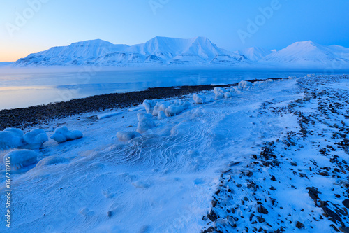 Winter Arctic. White snowy mountain, blue glacier Svalbard, Norway. Ice in ocean. Iceberg twilight in North pole. Beautiful landscape. Land of ice. Cold blue water nature.