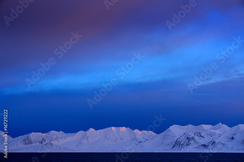 Winter Arctic. White snowy mountain, blue glacier Svalbard, Norway. Ice in ocean. Iceberg twilight in North pole. Pink clouds with ice floe. Beautiful landscape. Land of ice. Night ocean with ice.